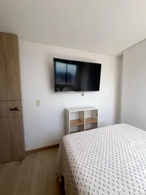 a bedroom with a bed and a tv on the wall at Apartamento moderno y acogedor en el corazón de Sabaneta in Sabaneta