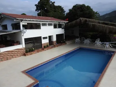 a villa with a swimming pool in front of a house at Finca la Irlanda in Manizales