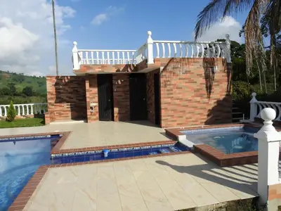 a villa with a swimming pool and a house at Finca la Irlanda in Manizales