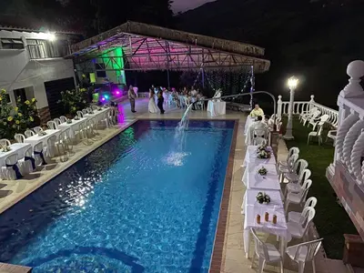 a pool with white tables and chairs and a fountain at Finca la Irlanda in Manizales