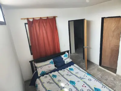 a bedroom with a bed with a red curtain and a door at Augusto Hernandez in Santa Fe de Antioquia