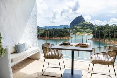 a patio with a table and chairs and a view of the water at MYLOS Hotel Boutique in Guatapé