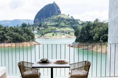 a table and chairs on a balcony with a view of a mountain at MYLOS Hotel Boutique in Guatapé