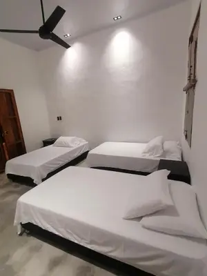 two beds in a room with white walls at Casa del Cable in Mariquita