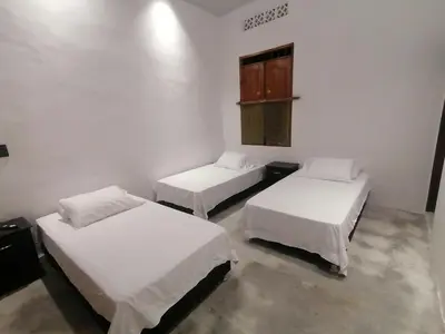a room with two beds and a small window at Casa del Cable in Mariquita
