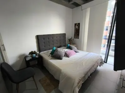 a bedroom with a bed with a chair and a window at Incleible Apartamento en Sabaneta in Sabaneta