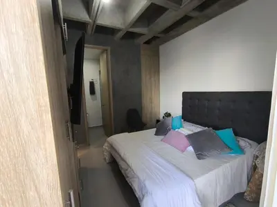 a bedroom with a large bed with blue and pink pillows at Incleible Apartamento en Sabaneta in Sabaneta