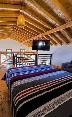 a bedroom with a large bed and a flat screen tv at Cabaña Solara in Jardin