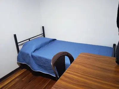 a bedroom with a bed with a blue blanket and a table at Residencias Universitarias La Casa de Lu sede Estrella in Manizales