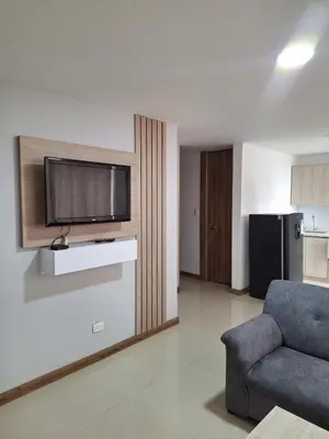 a living room with a couch and a tv on a wall at Apartment FL101 in Manizales