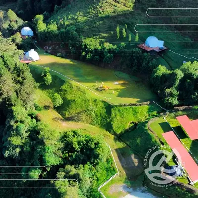 an aerial view of a farm with a field and a barn at Glamping Reserva del Ruiz in Villamaría