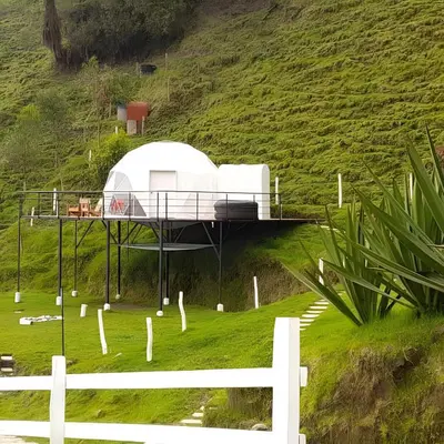 a house on the side of a hill at Glamping Reserva del Ruiz in Villamaría