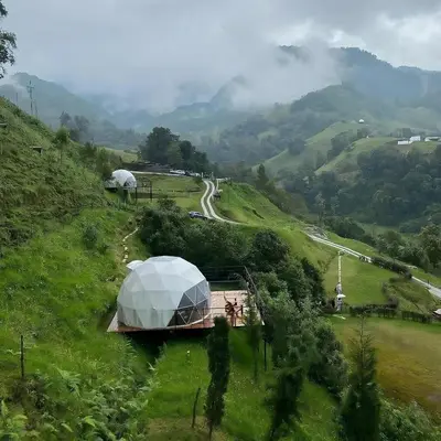 a field with a tent on a hill with a road at Glamping Reserva del Ruiz in Villamaría