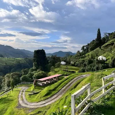 a winding road leading to a barn on a hill at Glamping Reserva del Ruiz in Villamaría