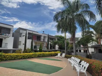 a row of white lawn chairs and a palm tree at Apartasol Familiar 2 in Santa Fe de Antioquia