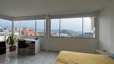 a bedroom with a bed and a desk and windows at Apartamento 3 habitaciones 2 baños Vista Panoramica - Av Santander Sector El Cable y Estadio Palogrande in Manizales