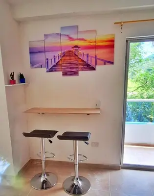 a room with two bar stools and a painting of a pier at OSIMiRI JAMAICA Ríos cristalinos, naturaleza y tranquilidad in San Rafael