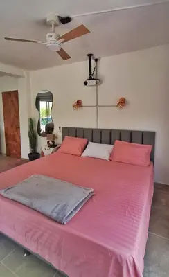 a bedroom with a large bed with pink sheets at OSIMiRI JAMAICA Ríos cristalinos, naturaleza y tranquilidad in San Rafael