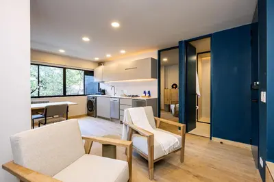 a living room with two chairs and a kitchen at StrataSix Hotel in Medellín