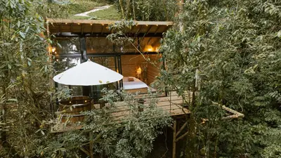 a tree house with a table and chairs in the woods at Onirico Refugio in Medellín