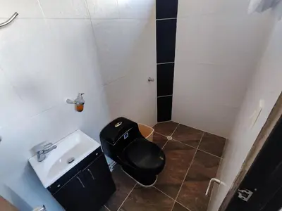 a bathroom with a black toilet and a sink at Spacious and calm place to stay in Santa Fe de Antioquia