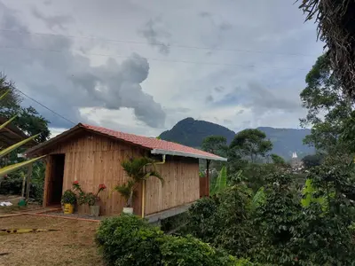 a small wooden house with mountains in the background at Cabaña octaluz in Jardin