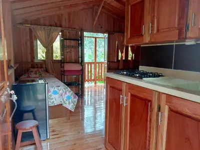 a kitchen with wooden cabinets and a bed in a room at Cabaña octaluz in Jardin