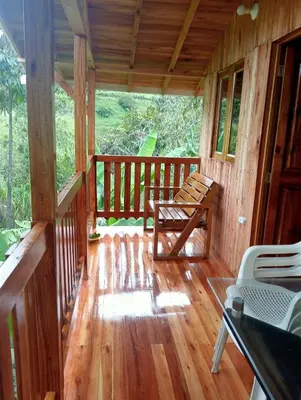 a porch of a cabin with a bench and a table at Cabaña octaluz in Jardin