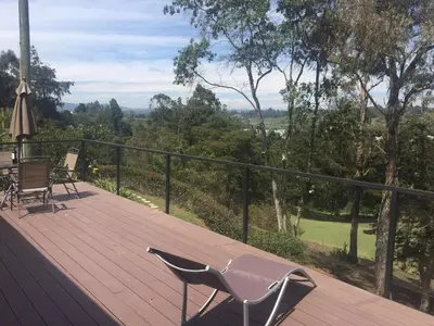 a wooden deck with a chair and a table and chairs at Espectacular Casa frente al campo de Golf in Rionegro