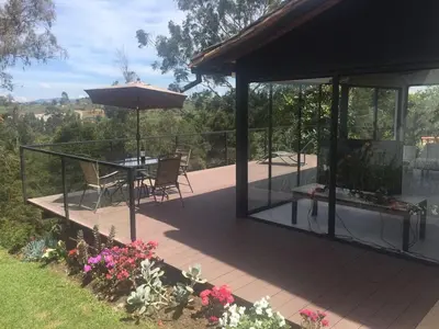 a patio with a table and an umbrella and some flowers at Espectacular Casa frente al campo de Golf in Rionegro