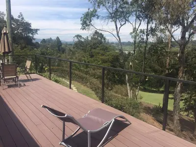a chair sitting on a wooden deck with a view at Espectacular Casa frente al campo de Golf in Rionegro