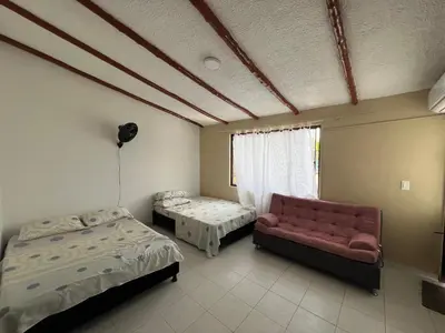 a room with two beds and a couch and a window at Jerusalén Hotel Boutique in Mariquita
