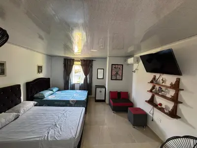a bedroom with two beds and a tv and a couch at Habitación la esmeralda in Puerto Triunfo