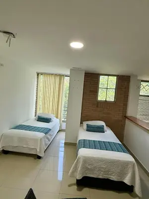 two beds in a room with two windows at Aparta hotel Montes in Medellín