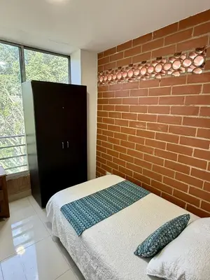 a bedroom with a brick wall and a bed at Aparta hotel Montes in Medellín