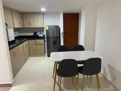 a kitchen with a white table and black chairs at Magnífico apto para disfrutar su estadia in Medellín