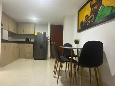 a kitchen with a table and chairs and a refrigerator at Magnífico apto para disfrutar su estadia in Medellín