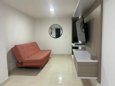 a living room with a red chair and a mirror at Magnífico apto para disfrutar su estadia in Medellín