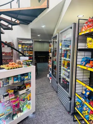 a store with two refrigerators and shelves of goods at Apartaestudio en el poblado cerca a Povenza 241 in Medellín