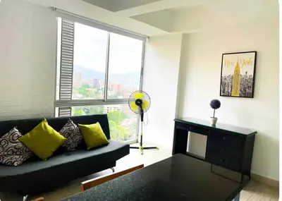 a living room with a couch and a large window at Apartaestudio en el poblado cerca a Povenza 241 in Medellín