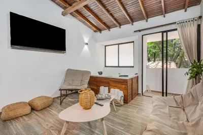 a living room with a tv and a couch and a table at CUMBIANA - Apt with Hot Tub on Provenza's Main Street in Medellín