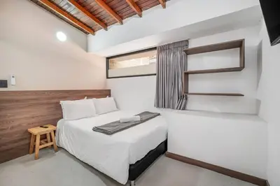 a bedroom with a white bed and a window at CUMBIANA - Apt with Hot Tub on Provenza's Main Street in Medellín