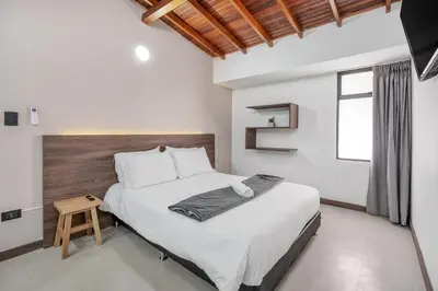a bedroom with a large bed with a wooden headboard at CUMBIANA - Apt with Hot Tub on Provenza's Main Street in Medellín