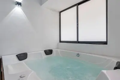 a bath tub in a room with two windows at CUMBIANA - Apt with Hot Tub on Provenza's Main Street in Medellín