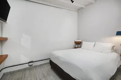 a bedroom with a white bed and a white wall at GAIRA - Provenza Walkable Area, AC & Balcony facing KarolG club in Medellín