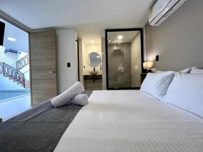 a bedroom with a large white bed and a bathroom at BALI - AC & Heated Pool in Provenza in Medellín