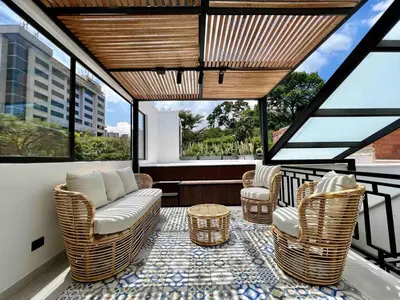 a balcony with wicker chairs and a table and windows at BORA BORA - Huge Jacuzzi, Rooftop & AC in Provenza in Medellín