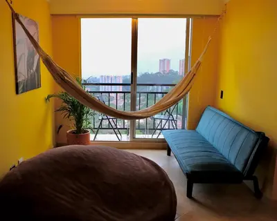 a bedroom with a blue couch and a large window at Coffee Retreat Peaceful Views and Local Soul in Medellín