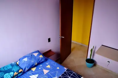 a bedroom with a bed with blue pillows and a door at Coffee Retreat Peaceful Views and Local Soul in Medellín