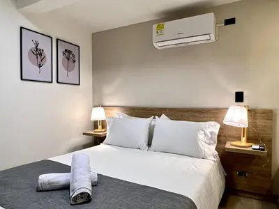 a bedroom with a white bed and a air conditioner at FIJI - Jacuzzi & Outdoor Lounge in Provenza in Medellín